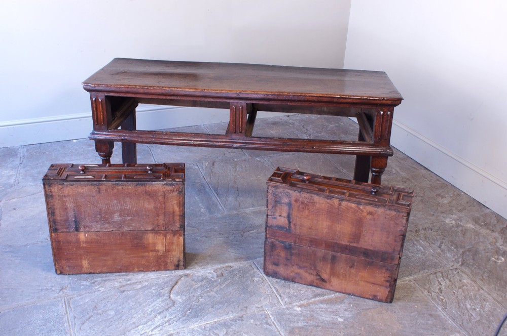 A 17th-century dark oak dresser base featuring geometric mitred mouldings across two drawers, turned front legs, and wooden drawer knobs. View IX