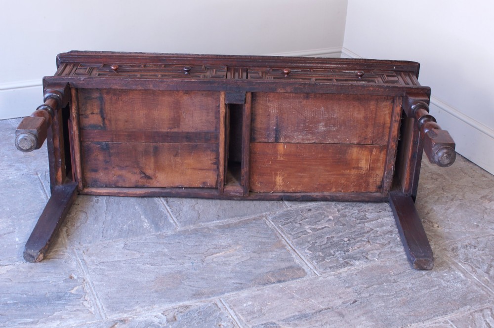 A 17th-century dark oak dresser base featuring geometric mitred mouldings across two drawers, turned front legs, and wooden drawer knobs. View XI