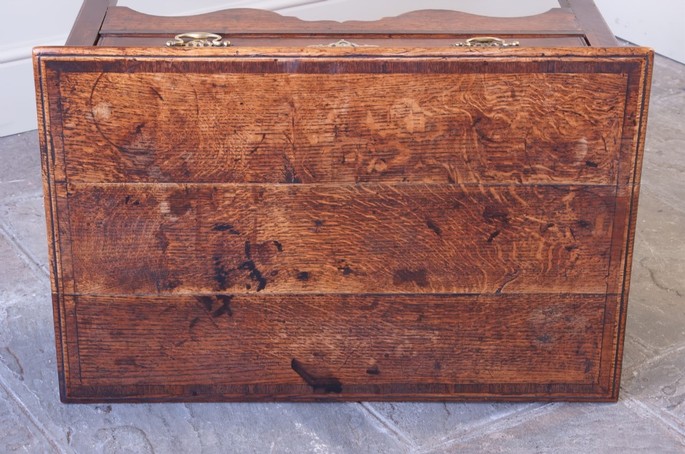 An 18th-century Georgian oak side table featuring a single drawer with decorative brass backplates and handles, set above a shaped apron and straight legs. View II