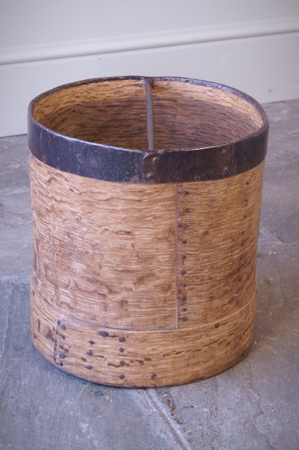 A cylindrical nineteenth-century French wooden grain measure with rustic iron banding, hand-riveted joints, and a central iron crossbar. View III