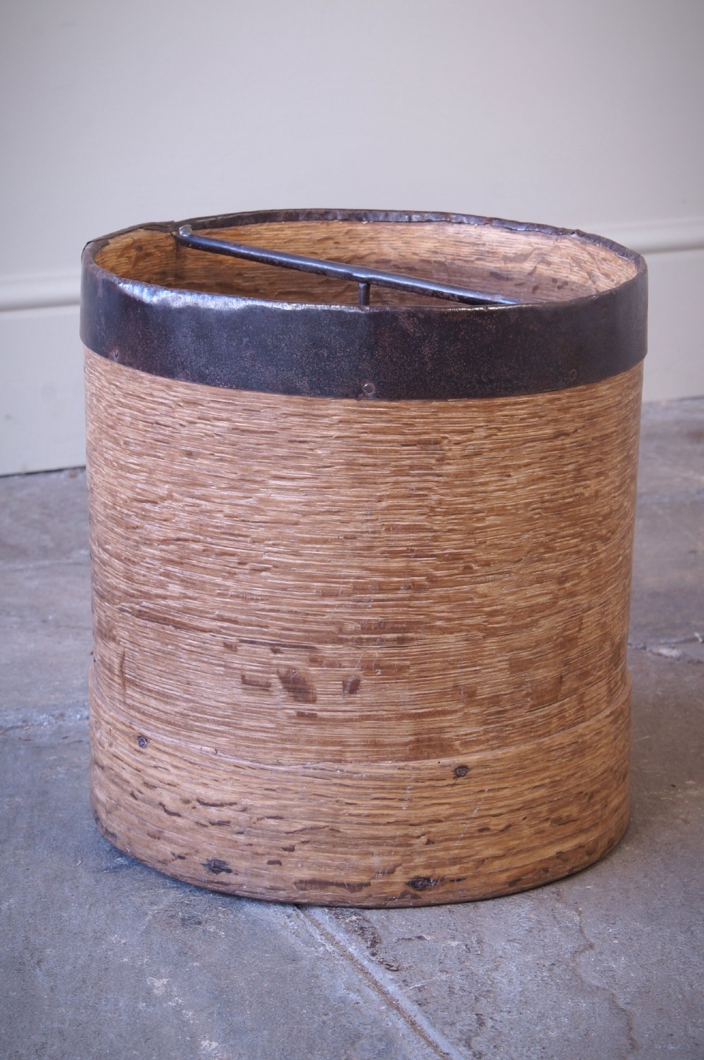 A cylindrical nineteenth-century French wooden grain measure with rustic iron banding, hand-riveted joints, and a central iron crossbar. View V