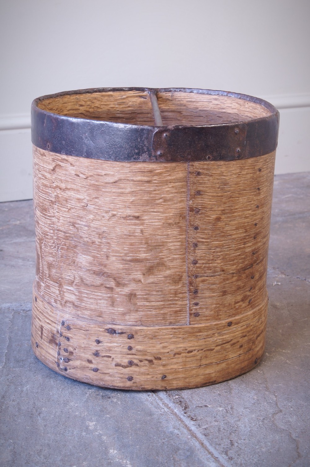 A cylindrical nineteenth-century French wooden grain measure with rustic iron banding, hand-riveted joints, and a central iron crossbar. View VI