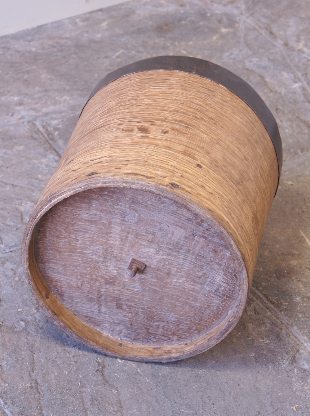 A cylindrical nineteenth-century French wooden grain measure with rustic iron banding, hand-riveted joints, and a central iron crossbar. View VII