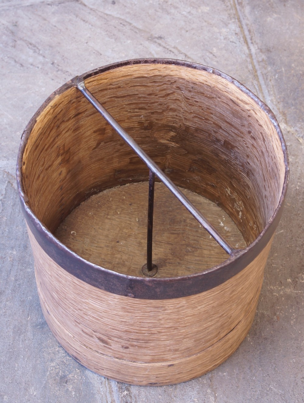 A cylindrical nineteenth-century French wooden grain measure with rustic iron banding, hand-riveted joints, and a central iron crossbar. View VIII