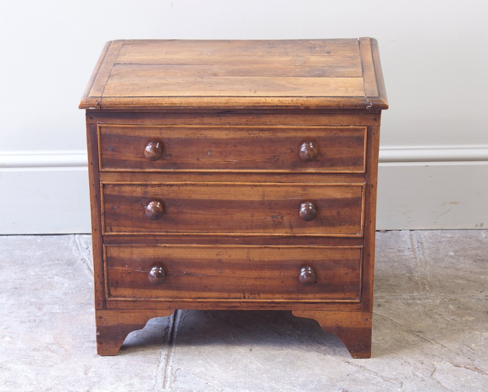 A Georgian plumwood close stool disguised as a small three-drawer chest with turned wooden knobs and bracket feet. View XII