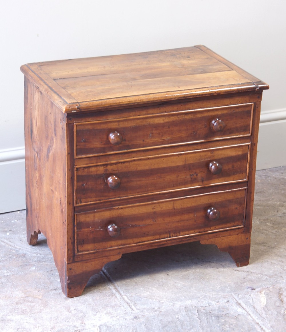 A Georgian plumwood close stool disguised as a small three-drawer chest with turned wooden knobs and bracket feet. View XIII