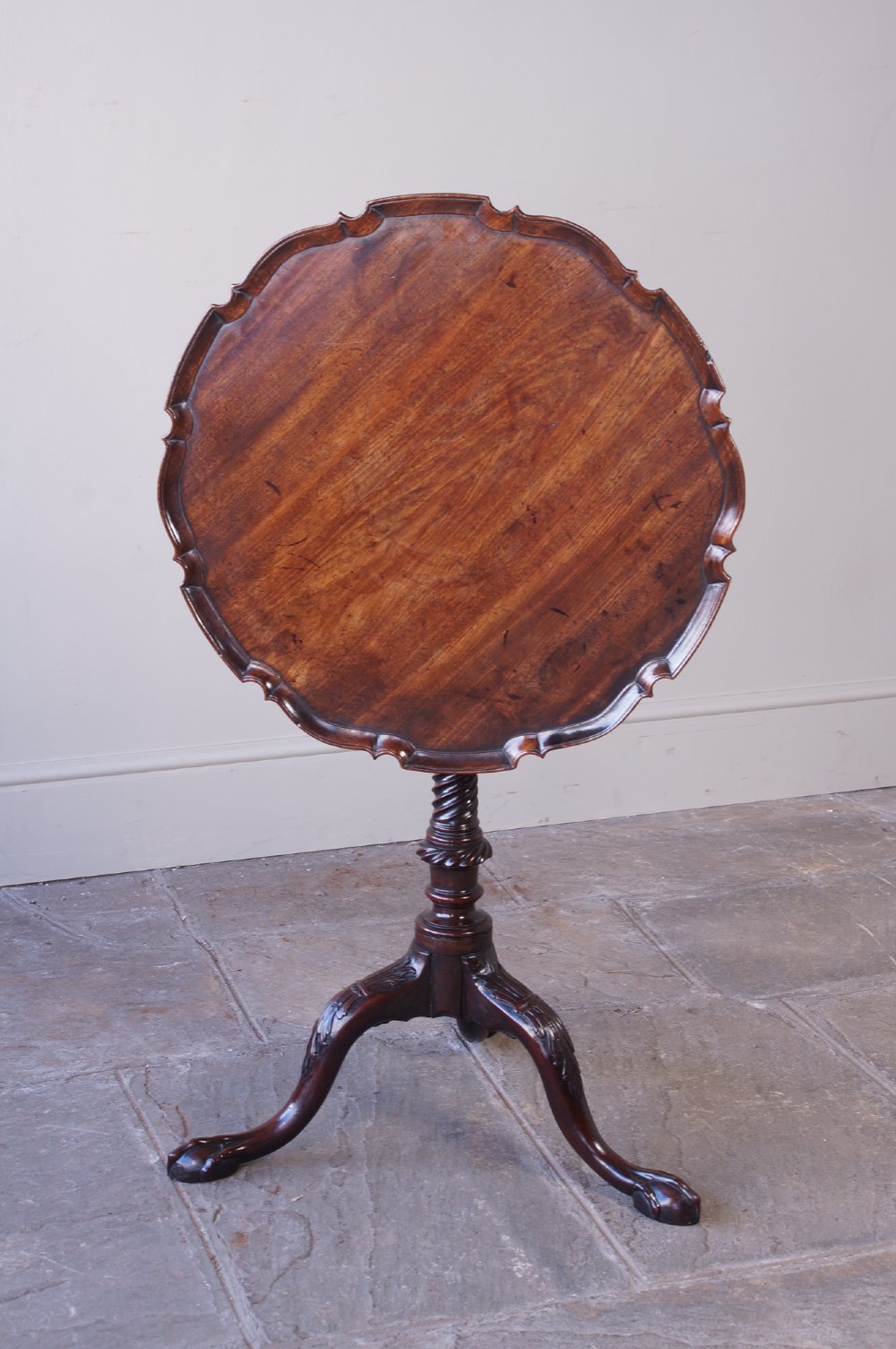 An 18th-century George III mahogany tripod table with a scalloped piecrust tilt-top, turned spiral column standard, and carved cabriole legs. View II