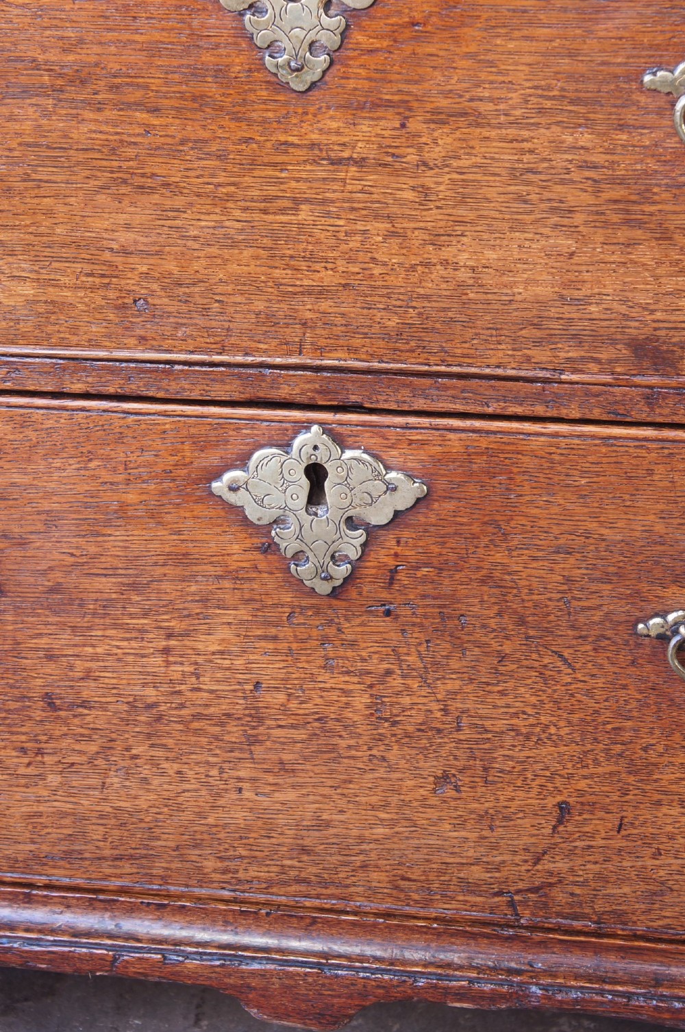 An early eighteenth-century oak chest of drawers featuring two short over three long drawers with brass drop handles and bracket feet. View III