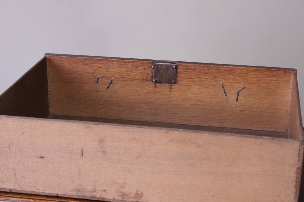 An early eighteenth-century oak chest of drawers featuring two short over three long drawers with brass drop handles and bracket feet. View VIII