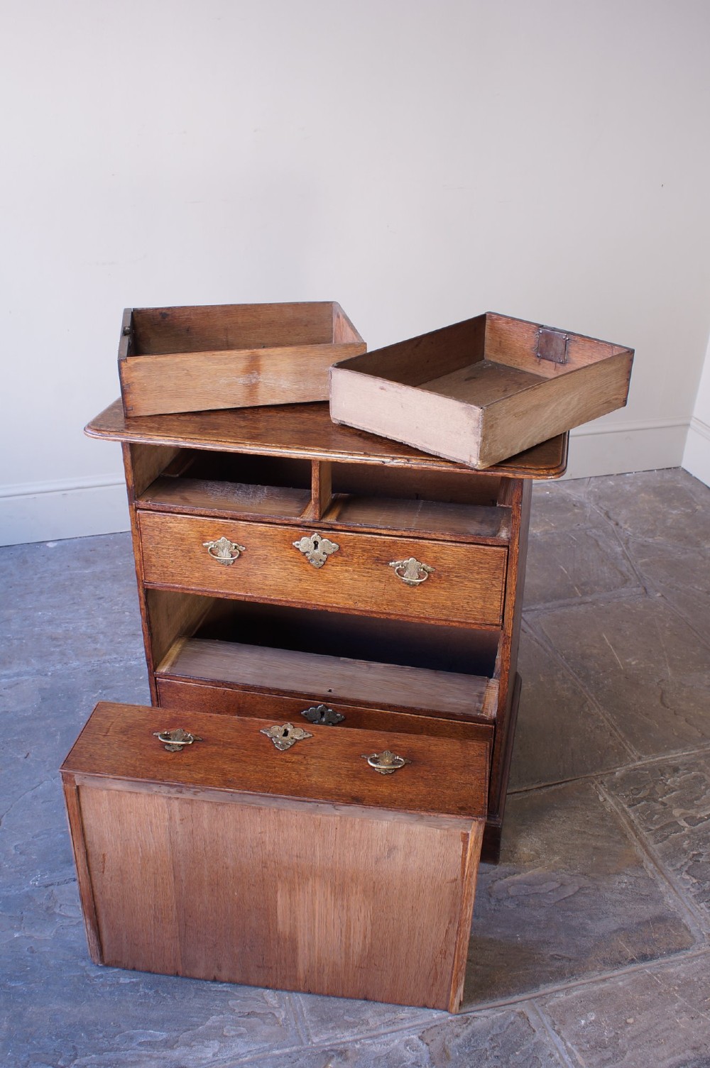 An early eighteenth-century oak chest of drawers featuring two short over three long drawers with brass drop handles and bracket feet. View XI