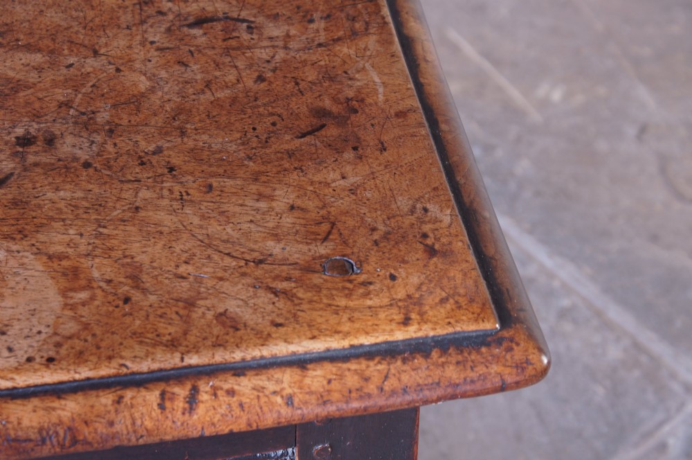 A 17th-century walnut joint stool featuring a rectangular moulded top, baluster turned legs, square pegged joinery, and a lower stretcher base with a dark patina. View V
