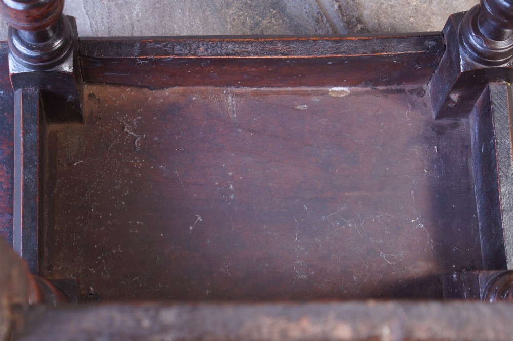 A 17th-century walnut joint stool featuring a rectangular moulded top, baluster turned legs, square pegged joinery, and a lower stretcher base with a dark patina. View XII