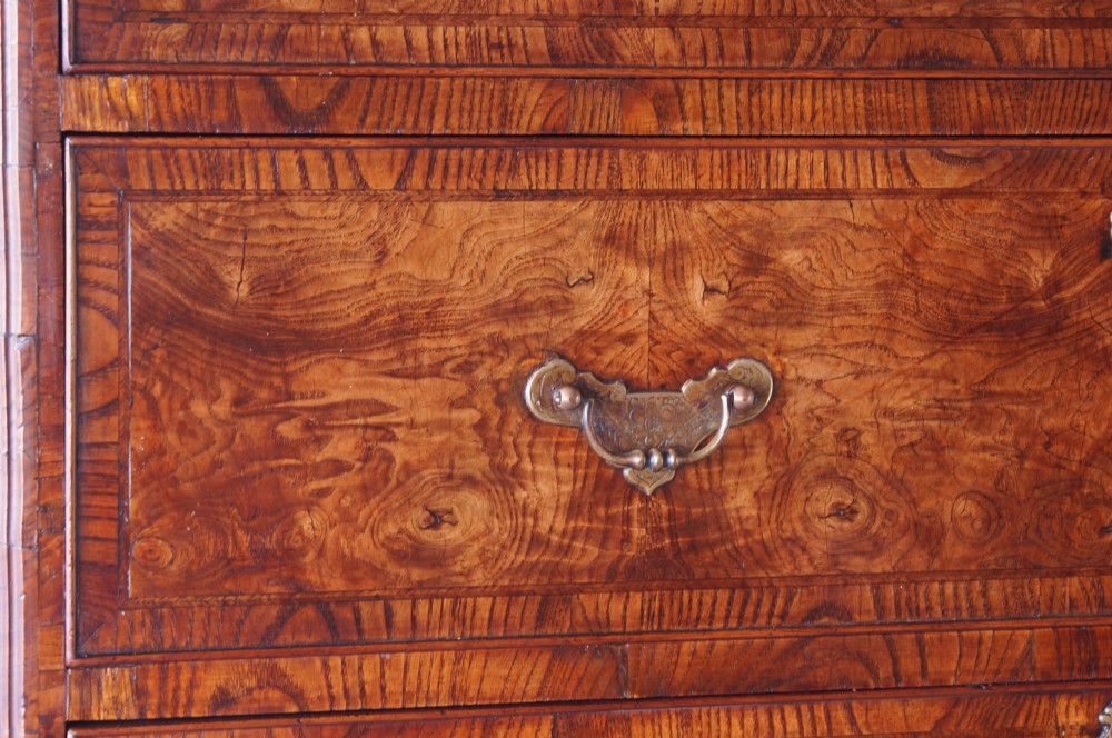 An 18th-century chest on chest crafted from figured ash featuring multiple graduated drawers with brass drop handles and bracket feet. View V