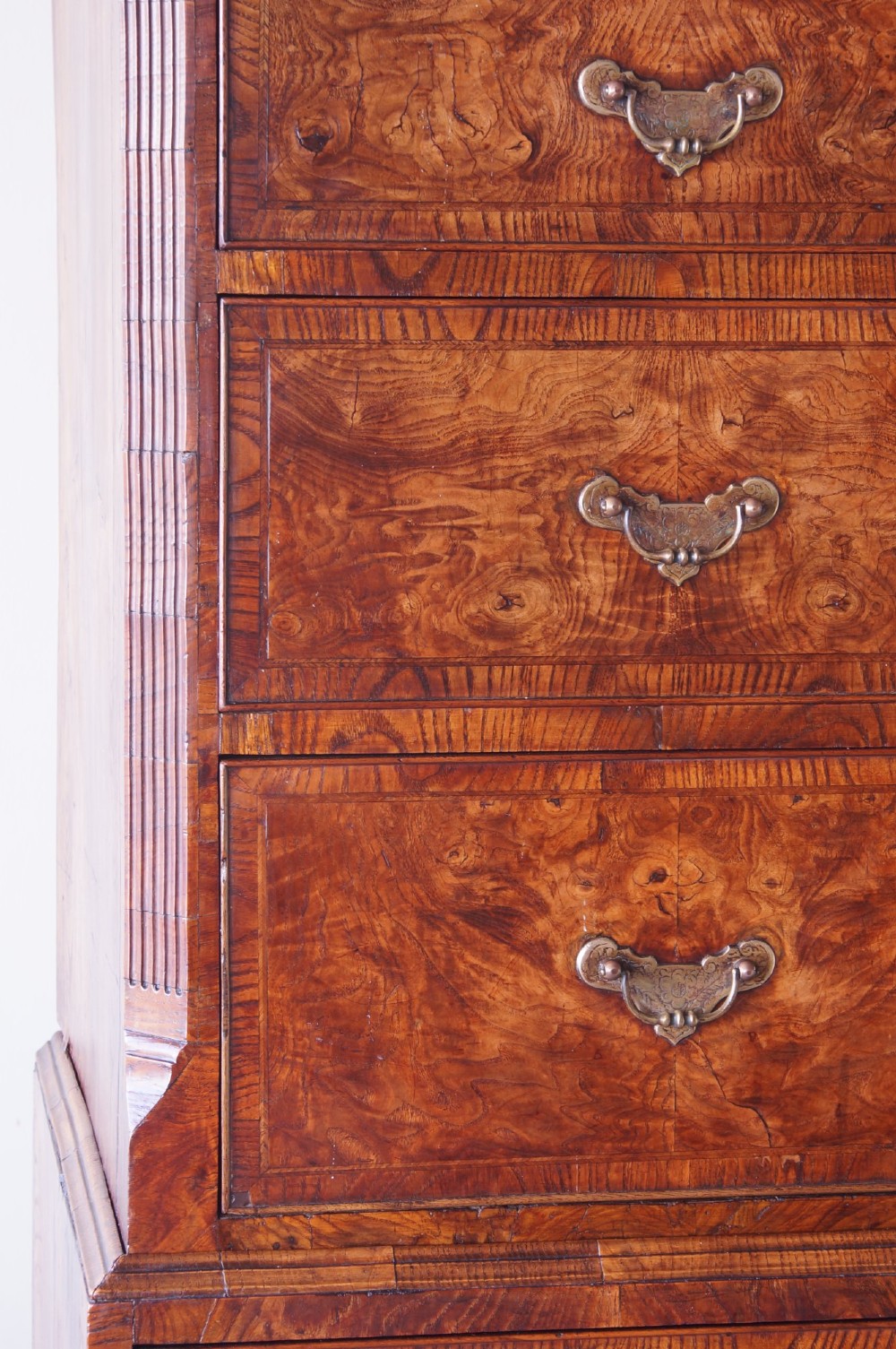 An 18th-century chest on chest crafted from figured ash featuring multiple graduated drawers with brass drop handles and bracket feet. View VII