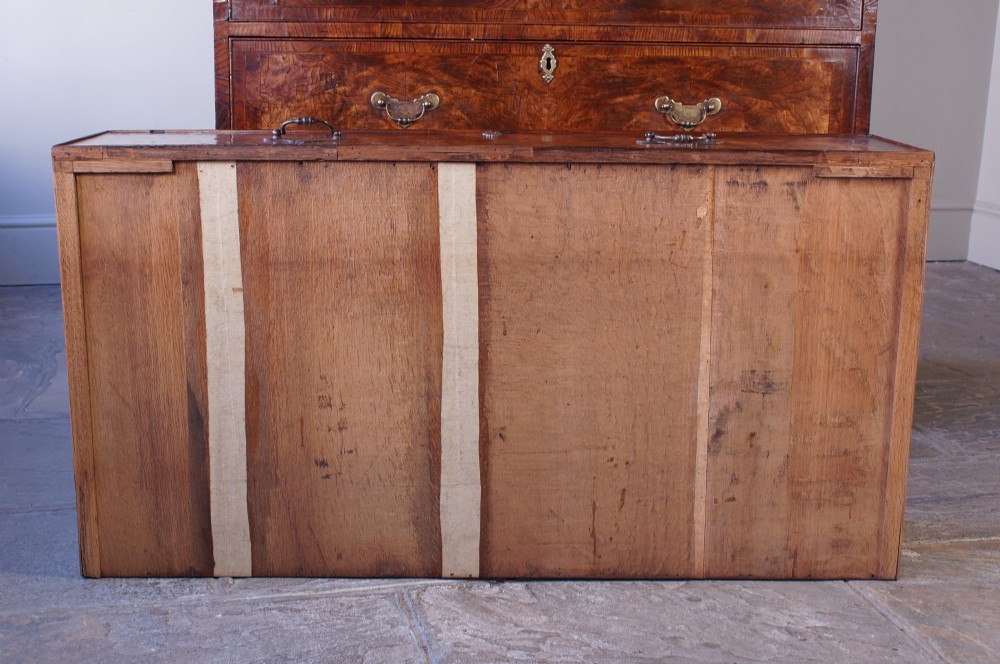 An 18th-century chest on chest crafted from figured ash featuring multiple graduated drawers with brass drop handles and bracket feet. View X