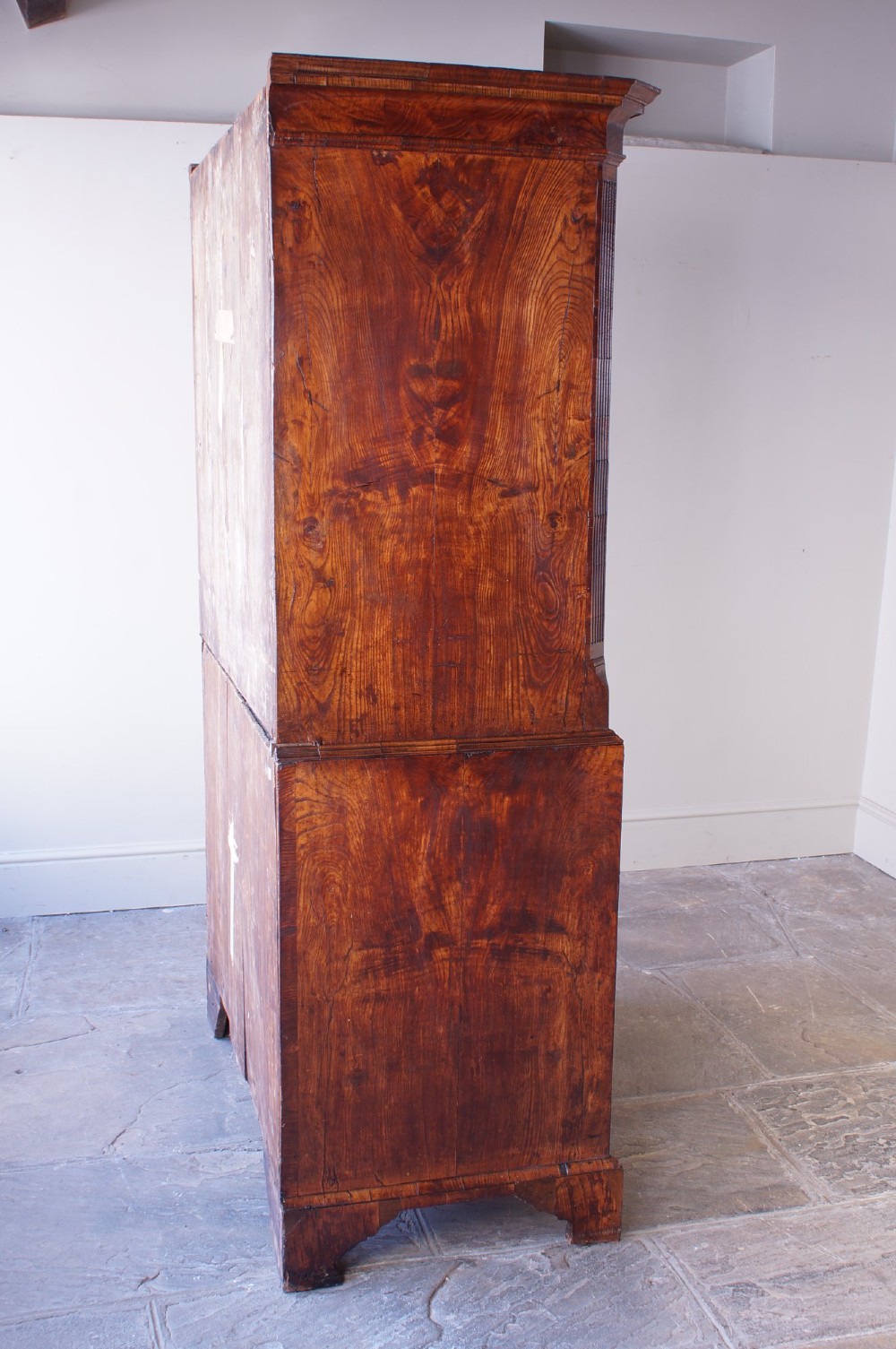 An 18th-century chest on chest crafted from figured ash featuring multiple graduated drawers with brass drop handles and bracket feet. View XI