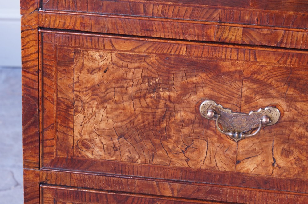 An 18th-century chest on chest crafted from figured ash featuring multiple graduated drawers with brass drop handles and bracket feet. View XII