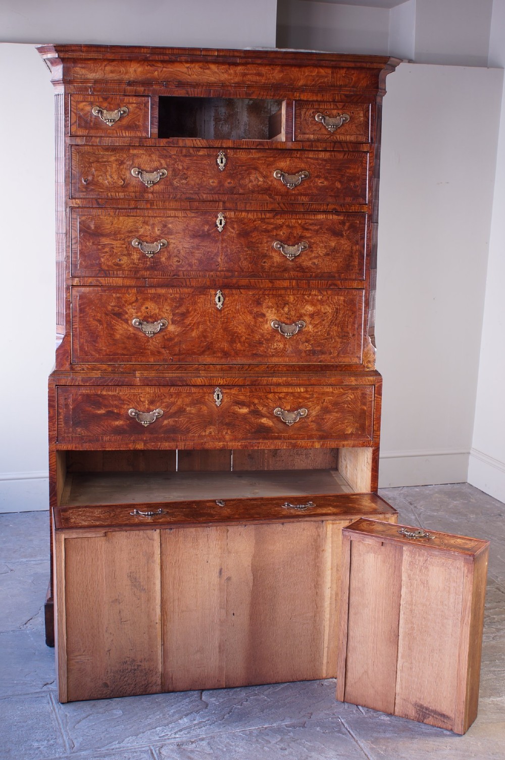 An 18th-century chest on chest crafted from figured ash featuring multiple graduated drawers with brass drop handles and bracket feet. View XV