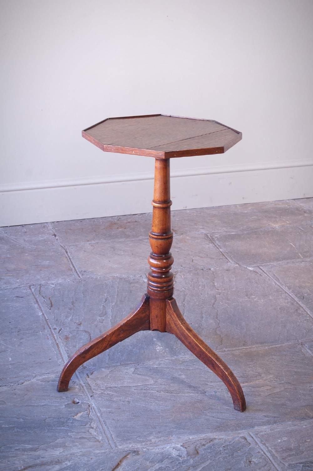 A Georgian oak and elm wine table featuring an octagonal top over a turned pedestal base with three down-swept tripod legs. View IV