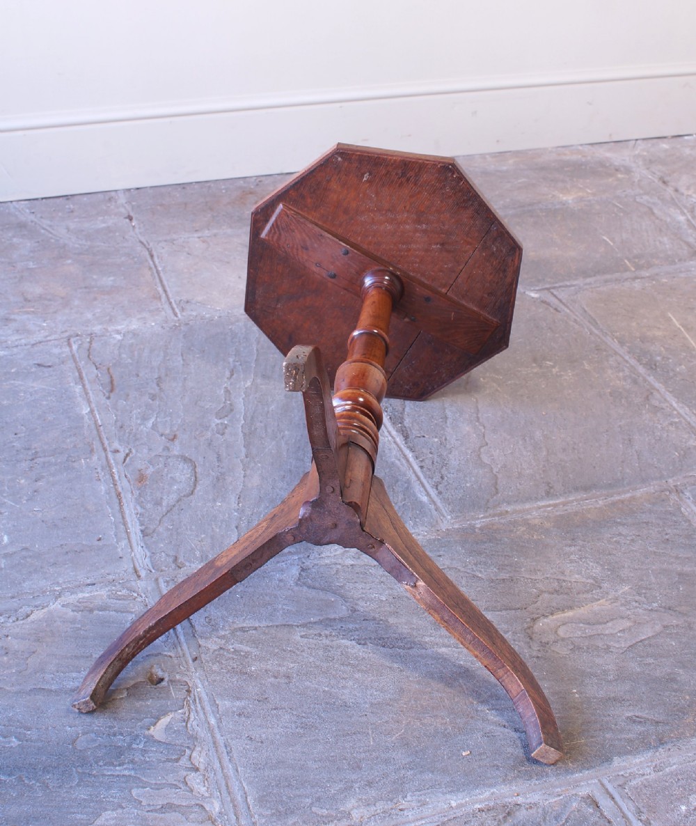 A Georgian oak and elm wine table featuring an octagonal top over a turned pedestal base with three down-swept tripod legs. View V
