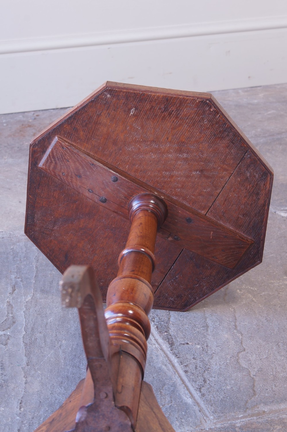 A Georgian oak and elm wine table featuring an octagonal top over a turned pedestal base with three down-swept tripod legs. View VI