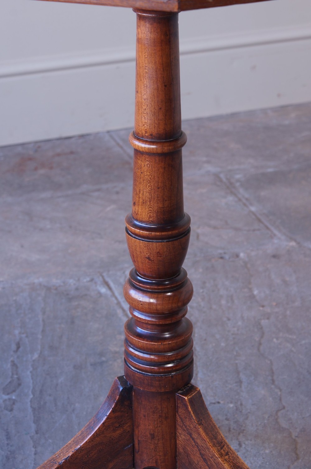 A Georgian oak and elm wine table featuring an octagonal top over a turned pedestal base with three down-swept tripod legs. View VII
