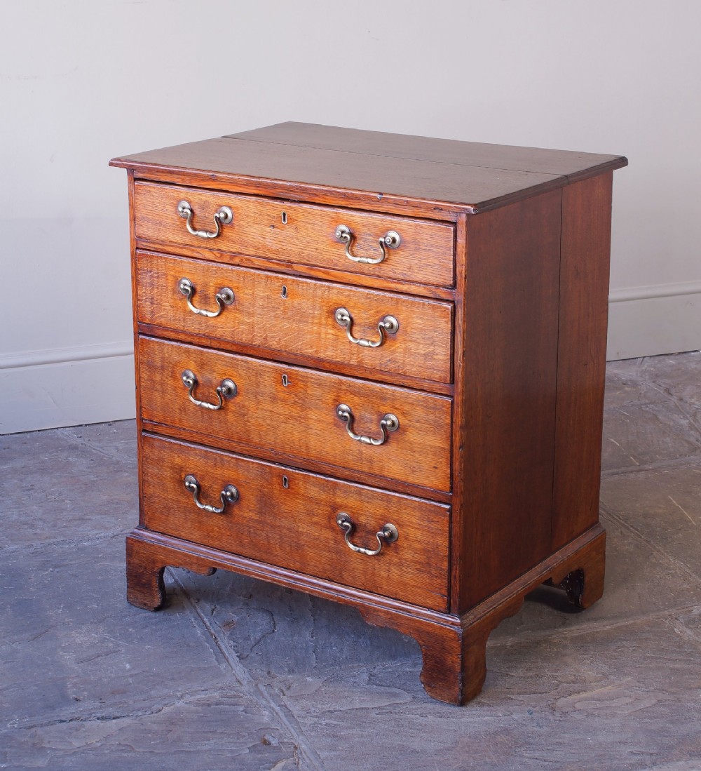 A small Georgian oak chest of drawers featuring four graduated drawers with brass swan-neck handles and bracket feet. View VI