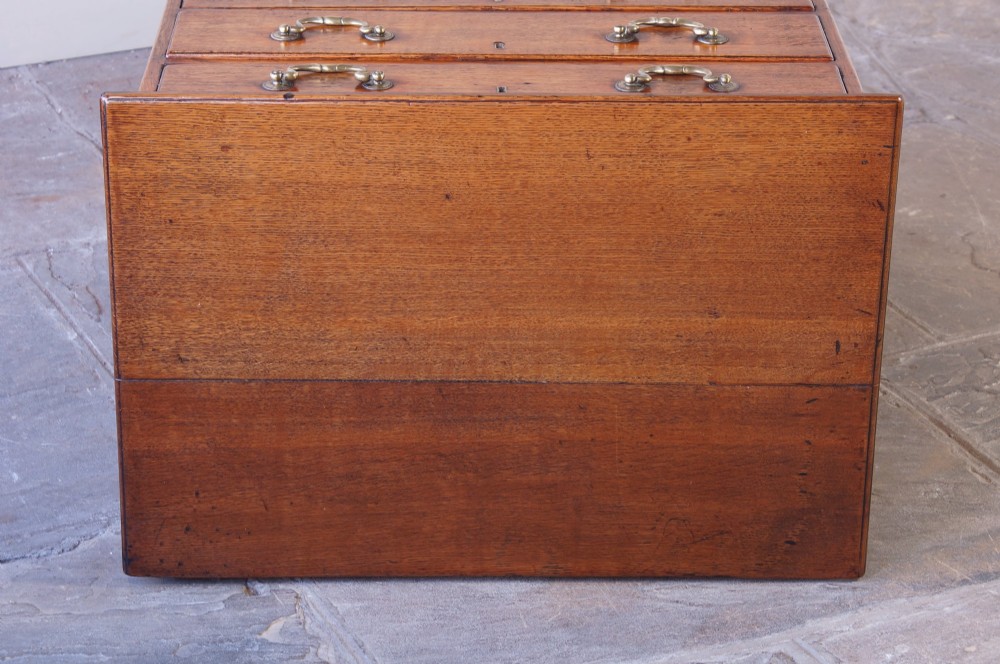 A small Georgian oak chest of drawers featuring four graduated drawers with brass swan-neck handles and bracket feet. View VIII