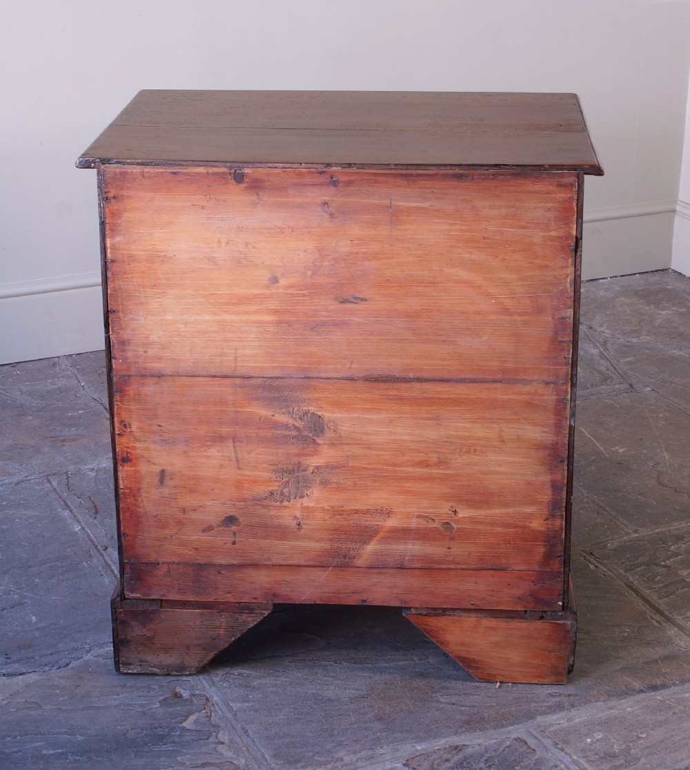 A small Georgian oak chest of drawers featuring four graduated drawers with brass swan-neck handles and bracket feet. View XII