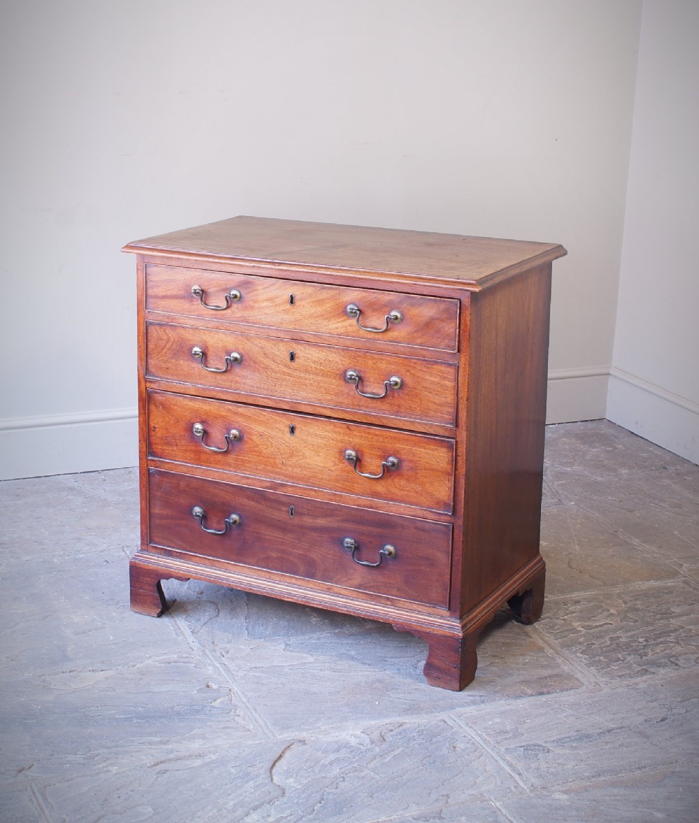 An 18th-century Georgian mahogany chest of drawers featuring four graduated drawers, brass swan-neck handles, keyhole escutcheons, and bracket feet.