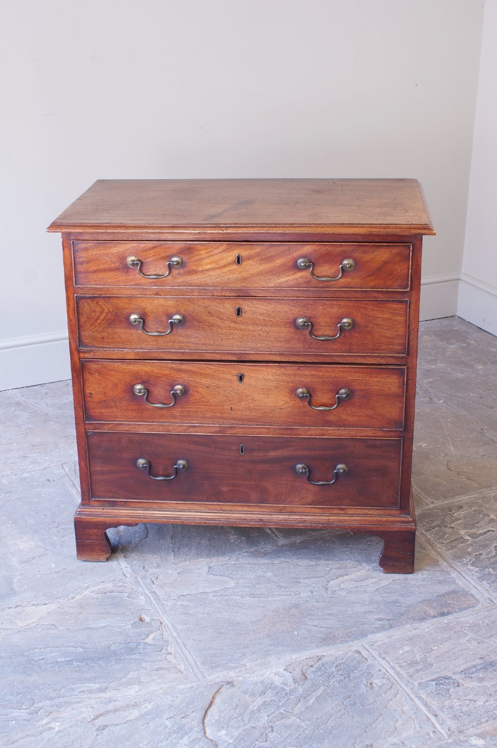 An 18th-century Georgian mahogany chest of drawers featuring four graduated drawers, brass swan-neck handles, keyhole escutcheons, and bracket feet. View II