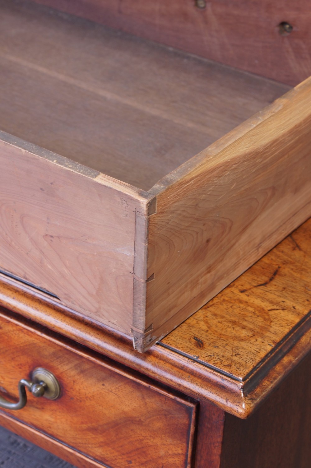 An 18th-century Georgian mahogany chest of drawers featuring four graduated drawers, brass swan-neck handles, keyhole escutcheons, and bracket feet. View VII