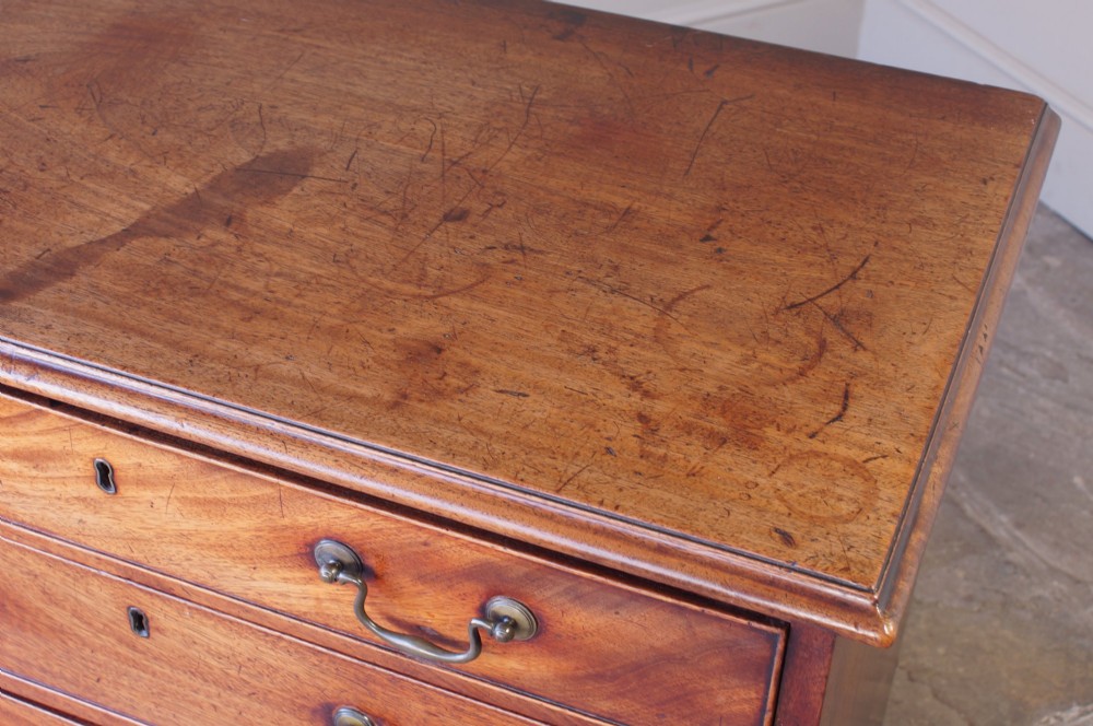 An 18th-century Georgian mahogany chest of drawers featuring four graduated drawers, brass swan-neck handles, keyhole escutcheons, and bracket feet. View X
