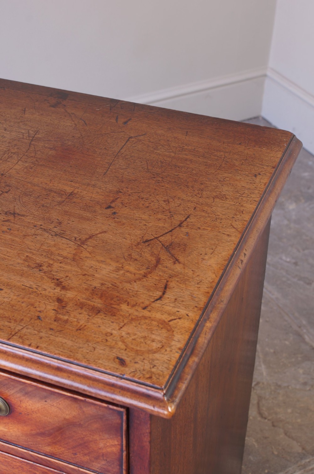 An 18th-century Georgian mahogany chest of drawers featuring four graduated drawers, brass swan-neck handles, keyhole escutcheons, and bracket feet. View XI