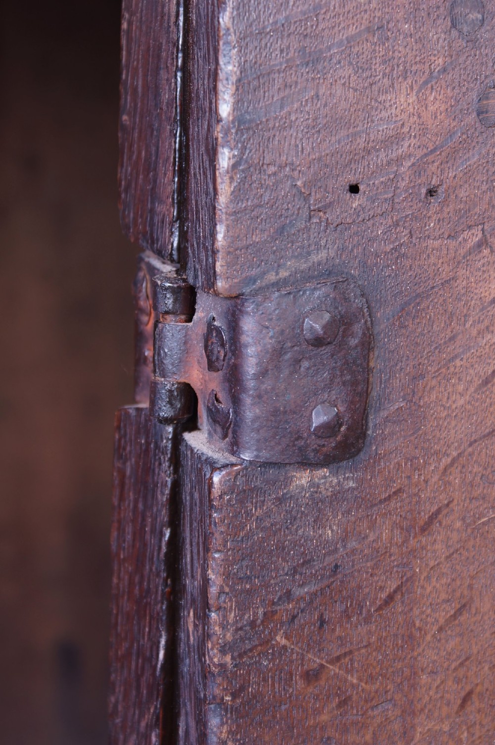 A 17th-century dark oak dresser base featuring three drawers above panelled cupboard doors with geometric moulding and brass drop handles. View XIV