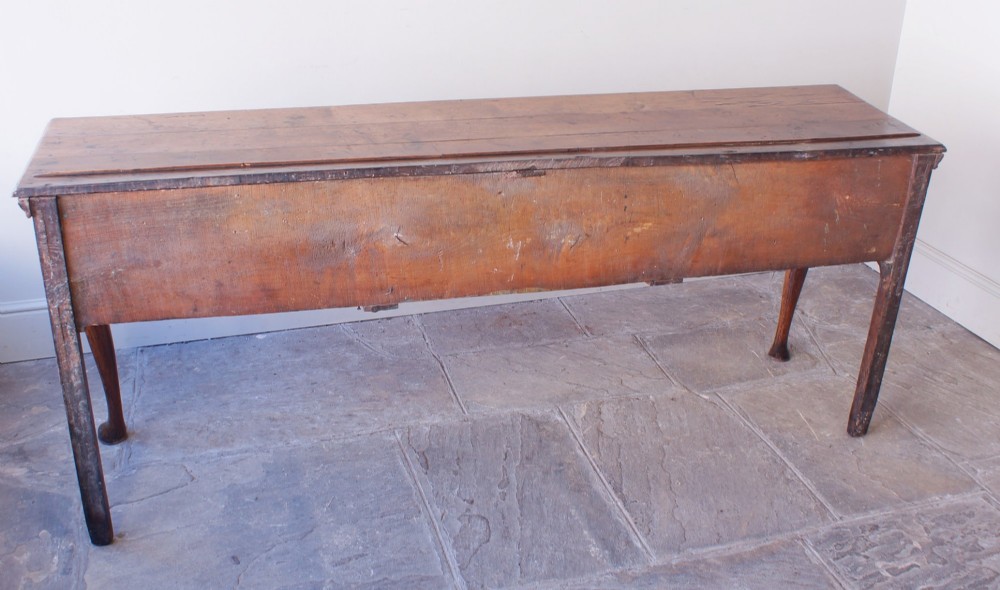 An eighteenth-century oak dresser base featuring three crossbanded drawers with brass handles, a shaped scalloped apron, and slender cabriole legs. View IX