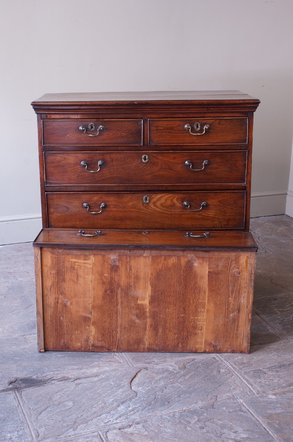 An eighteenth-century fruitwood chest of drawers with two short over three long graduated drawers, brass swan-neck handles, keyhole escutcheons, and shaped bracket feet. View V