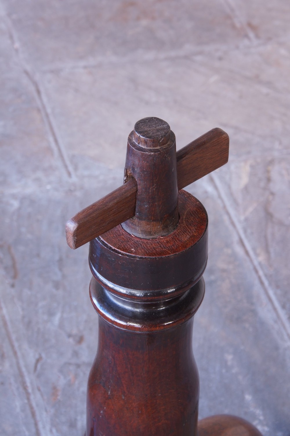 A Georgian oak tilt-top table with a circular planked top shown tilted vertically on a turned pedestal stem and tripod legs. View III