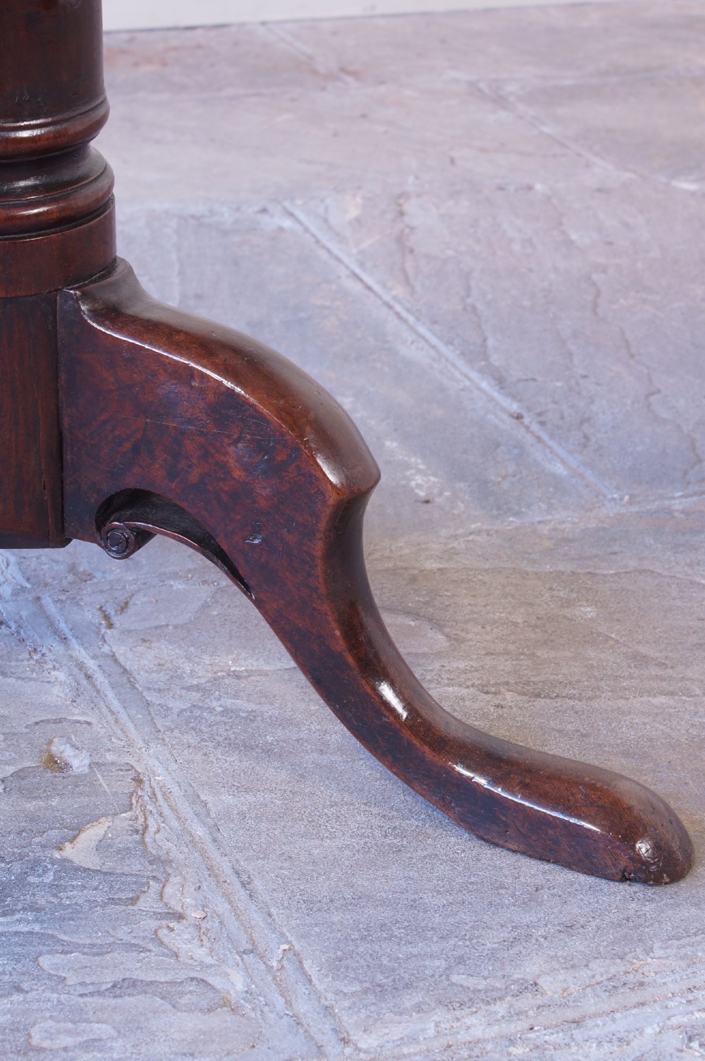 A Georgian oak tilt-top table with a circular planked top shown tilted vertically on a turned pedestal stem and tripod legs. View VII