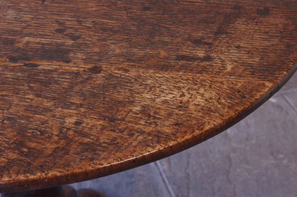 A Georgian oak tilt-top table with a circular planked top shown tilted vertically on a turned pedestal stem and tripod legs. View VIII