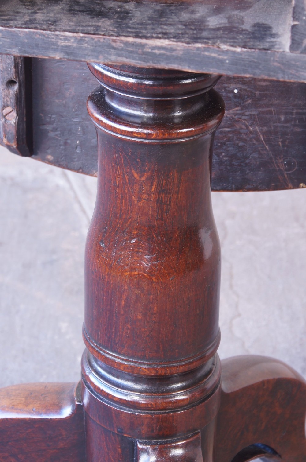 A Georgian oak tilt-top table with a circular planked top shown tilted vertically on a turned pedestal stem and tripod legs. View XII