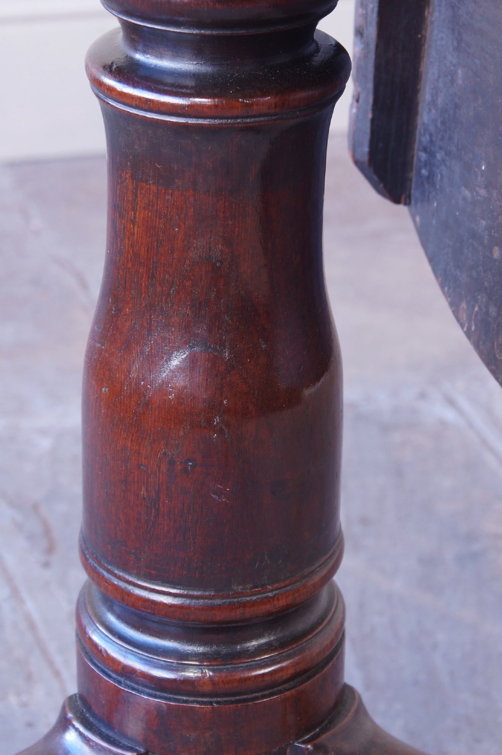 A Georgian oak tilt-top table with a circular planked top shown tilted vertically on a turned pedestal stem and tripod legs. View XIII