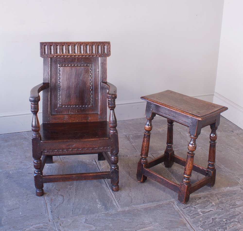 A dark brown 17th-century oak childs wainscot armchair with carved geometric back panels and turned supports. View II