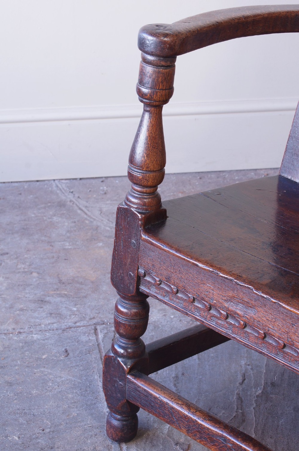 A dark brown 17th-century oak childs wainscot armchair with carved geometric back panels and turned supports. View IV