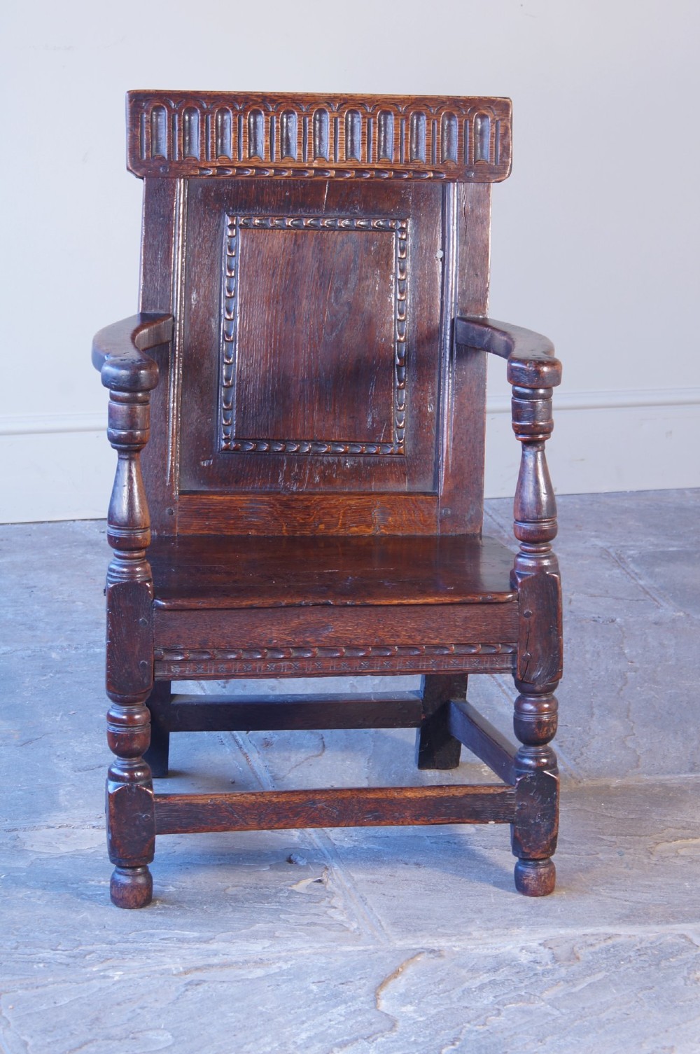 A dark brown 17th-century oak childs wainscot armchair with carved geometric back panels and turned supports. View VI
