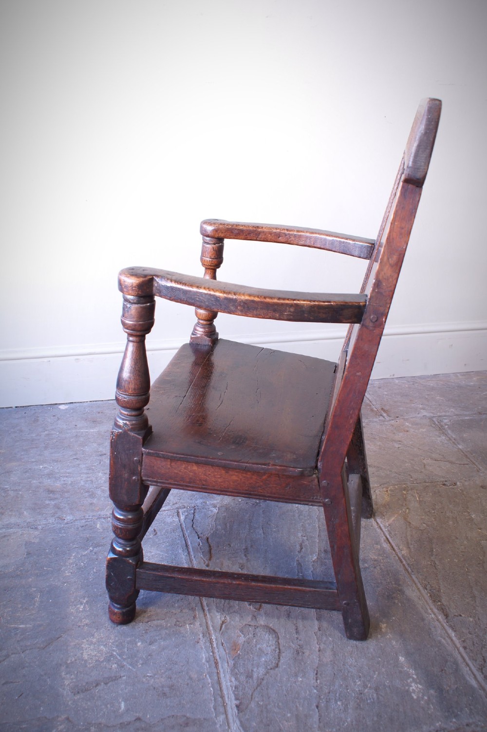 A dark brown 17th-century oak childs wainscot armchair with carved geometric back panels and turned supports. View VIII