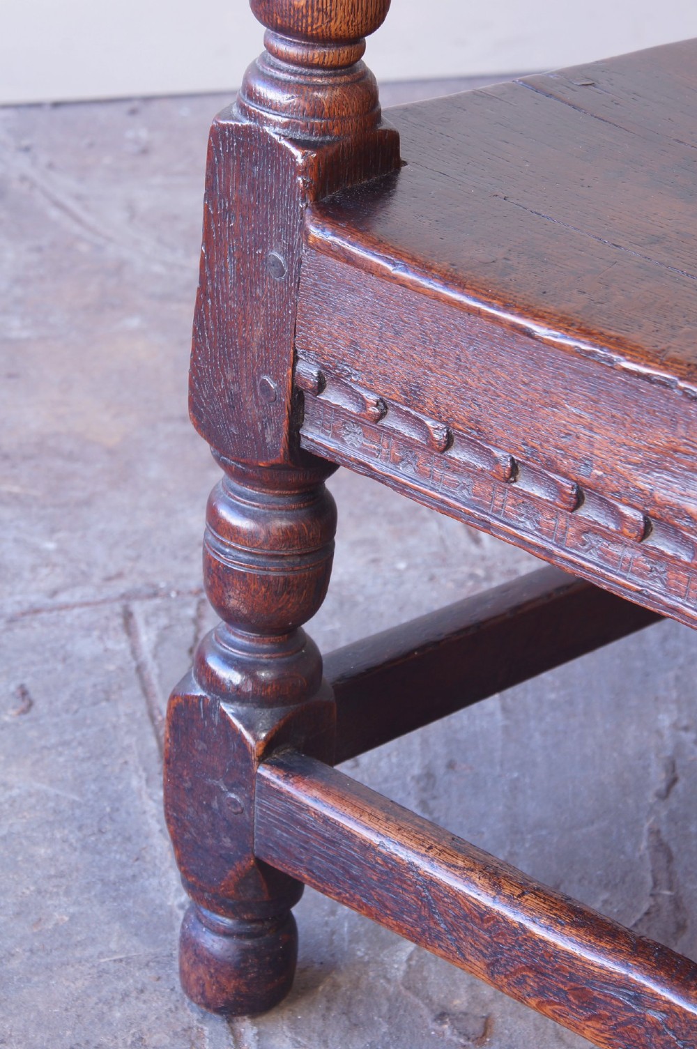 A dark brown 17th-century oak childs wainscot armchair with carved geometric back panels and turned supports. View IX