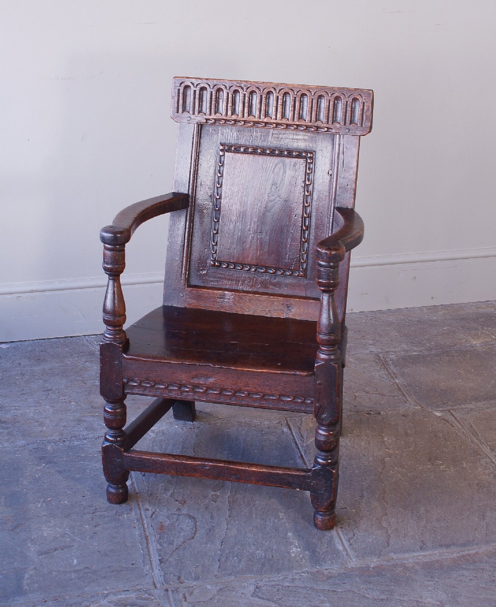 A dark brown 17th-century oak childs wainscot armchair with carved geometric back panels and turned supports. View XI
