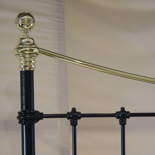 fig 1. A Victorian-style black iron and brass bedstead with vertical spindles, decorative brass finials, and a curved brass top rail.