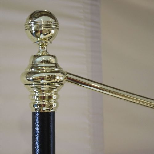 fig 2. A Victorian-style black iron and brass bedstead with vertical spindles, decorative brass finials, and a curved brass top rail.